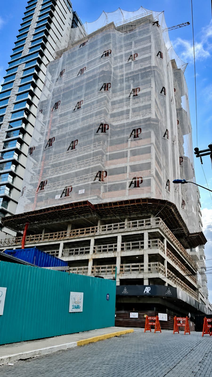 Edifício corporativo de múltiplos pavimentos em construção protegido por tela fachadeira em Curitiba